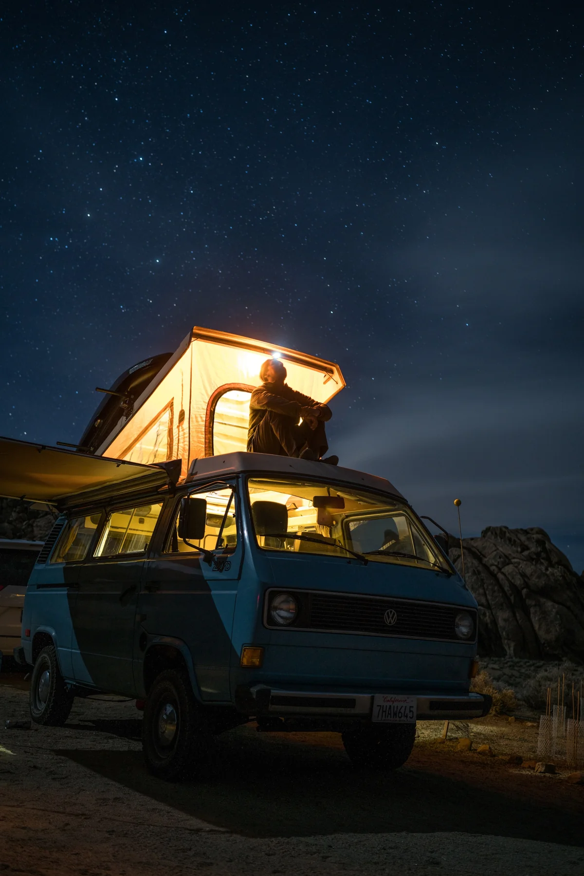 Campervan with warm interior lights parked outdoors at night